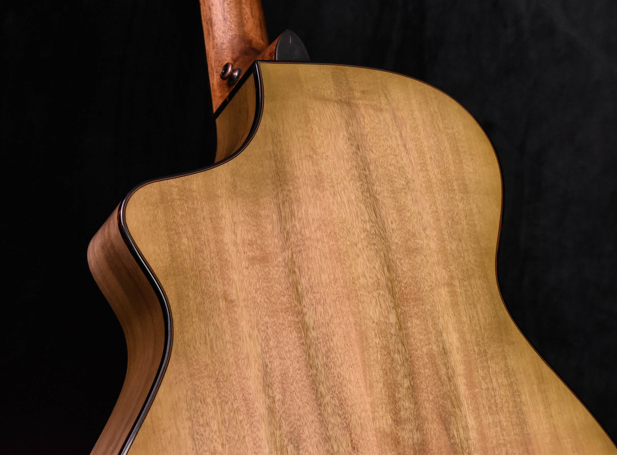 Natural wood concert guitar body with black edge binding near neck joint